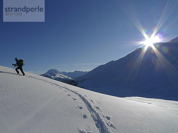 Ein Skibergsteiger wandert im Hinterland der Schweizer Walliser Alpen. (Sonnenlicht)