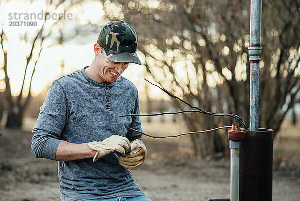 Nahaufnahme eines Mannes  der lächelt  während er draußen Elektroarbeiten erledigt