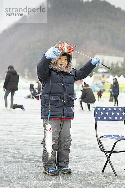 Kleiner Junge freut sich über Fisch  der beim Eisfischerfest in Hwacheon Sancheoneo  Gangwon-do  Südkorea  gefangen wurde