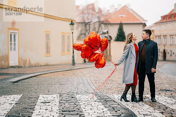 Junges Paar geht mit Luftballons im Herzen durch Prag