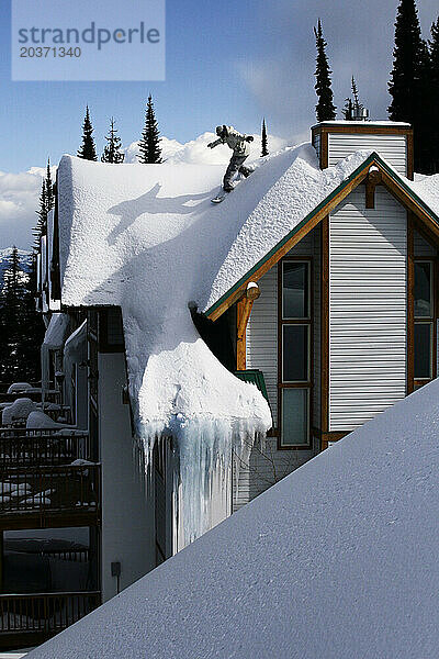 Junger Erwachsener fährt mit dem Snowboard ein Haus in Idaho hinunter.