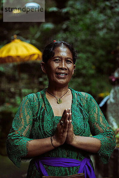 Balinesische Frau in traditioneller Kleidung betet zeremoniell im Tempel auf Bali.