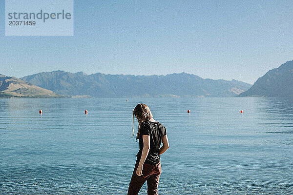 Ein Mädchen steht isoliert im ruhigen  welligen blauen Wasser in Neuseeland