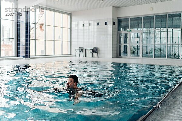 Ein 40-jähriger Mann schwimmt in einem Pool mit Blick auf Prag