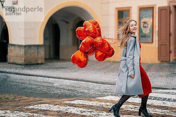 Junge Frau geht mit Luftballons im Herzen durch Prag