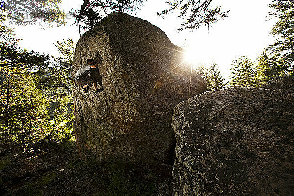Ein sportlicher junger Mann arbeitet bei Sonnenuntergang in Montana an einem Boulderproblem.