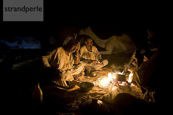 Camel herders gather for dinner in the evening as they travel through the Sahara desert  Sudan on a camel caravan.