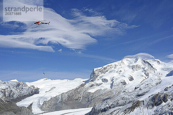 Ein Rettungshelikopter der Bergrettung Air Zermatt bei einem sogenannten Longline-Einsatz in den Schweizer Alpen.