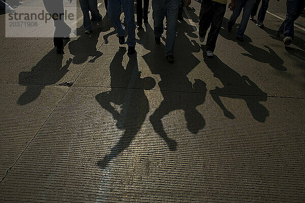 The shadow of electricians is cast on the road as they protest the government's shut down of a state-run power company in Mexico City