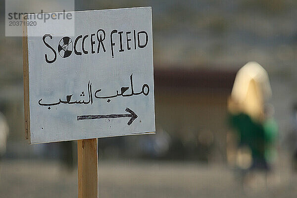 Ein Schild auf Arabisch und Englisch zeigt die Richtung zum Fußballplatz