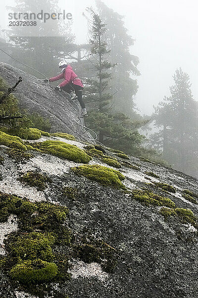 Eine Frau bewegt ihren Klettersteig zum nächsten Seil  während sie den Via Ferrata in Squamish  British Columbia  erklimmt.