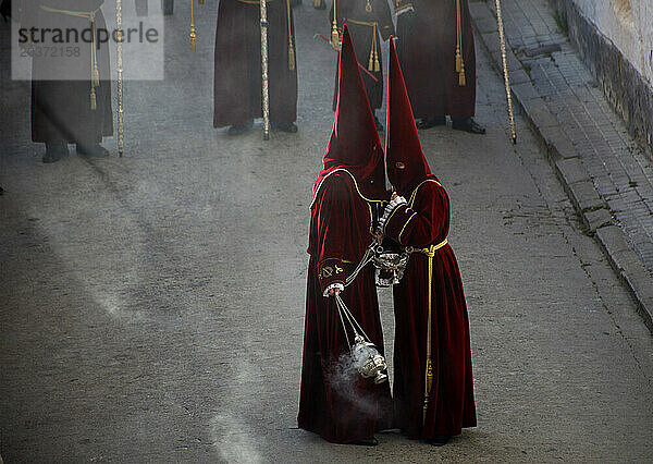 Messdiener tragen rote Kleidung und spitze Kapuzen und unterhalten sich während der Osterwochenfeierlichkeiten in Baeza  Provinz Jaen  Andalusien  Spanien