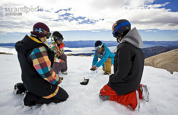 Ein professioneller Snowboarder zeigt einer Gruppe von Mädchen eine Demonstration eines Lawinenverschüttetensuchgeräts