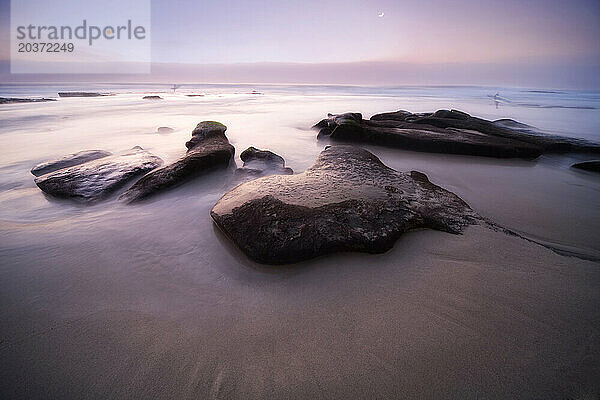 Ein kalifornischer Strand mit erodierten Felsen bei Sonnenuntergang.