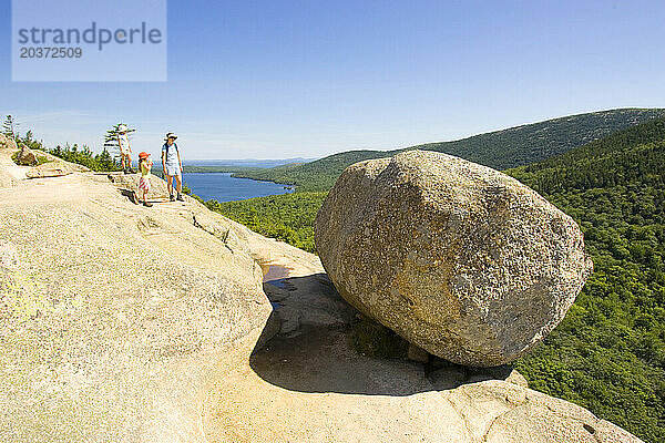 Drei Personen betrachten die Aussicht vom Gipfel des Bubble Mountain im Acadia-Nationalpark in Maine.