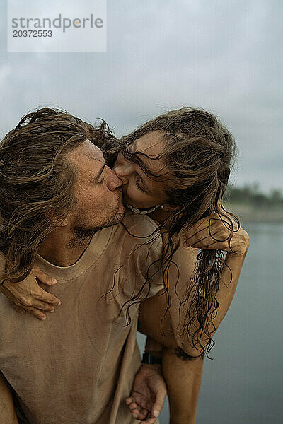 Junges fröhliches  glückliches verliebtes Paar  das sich am Strand küsst.