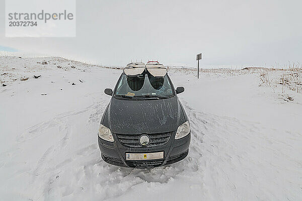 Zwei Surfbretter auf dem Dach eines Kleinwagens im Schnee