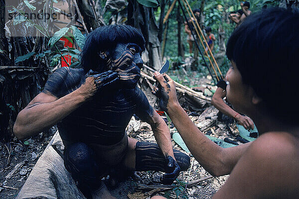 Ein Yanomami-Indianer lässt sich als Vorbereitung für ein Fest das Gesicht bemalen. Im Amazonaswald im Süden Venezuelas.