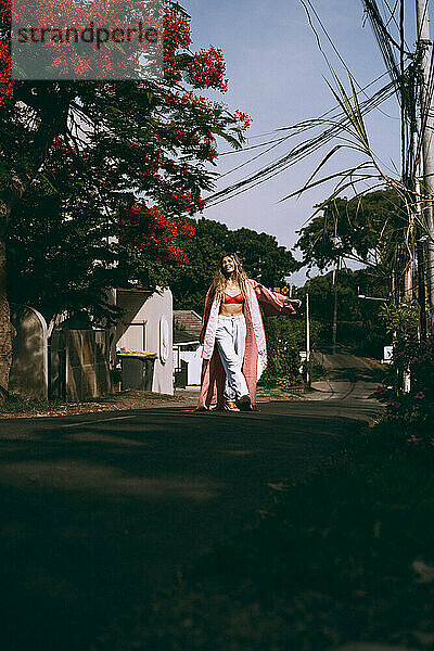 Junge Frau mit langen Haaren im Kimono geht auf Bali die Straße entlang.