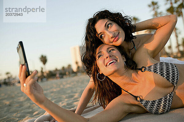 Zwei Frauen machen ein Foto von sich selbst am Strand.