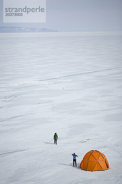 Zwei Menschen bauen im Winter in Sibirien  Russland  ihr Zelt auf dem zugefrorenen Baikalsee auf.