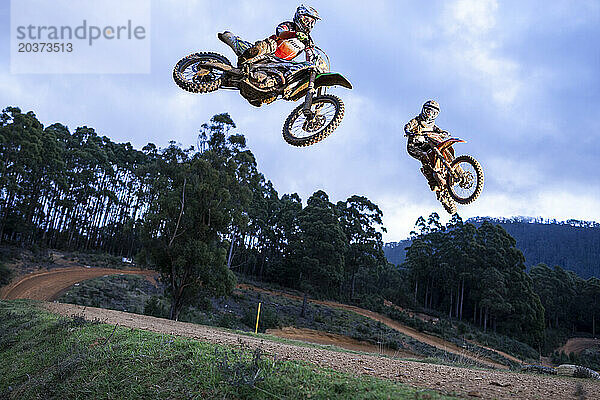 Zwei Dirtbike-Rennfahrer springen auf dem Tisch.