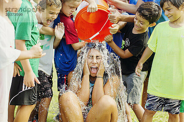 Kinder im Sommercamp in San Diego  Kalifornien  schütten einen Eimer Wasser über eines von ihnen.