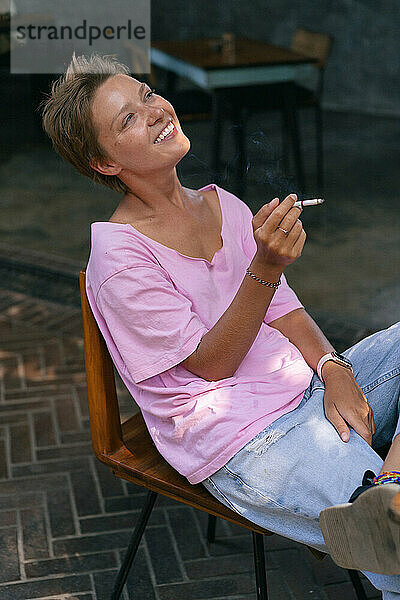 Glücklich lachende Frau  die eine Zigarette raucht.