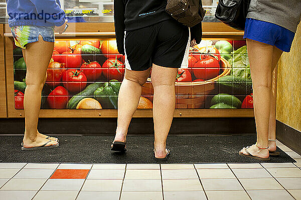 Appleton  Wisconsin  Vereinigte Staaten. Übergewichtiger Teenager und ihre Freunde bekommen Sandwiches bei Subway (Grafik  nur Beine).