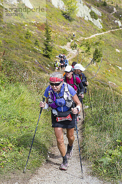 Eine ältere Frau läuft in den Hügeln von Chamonix. Sie steht kurz davor  das äußerst anstrengende UTMB-Rennen zu beenden.