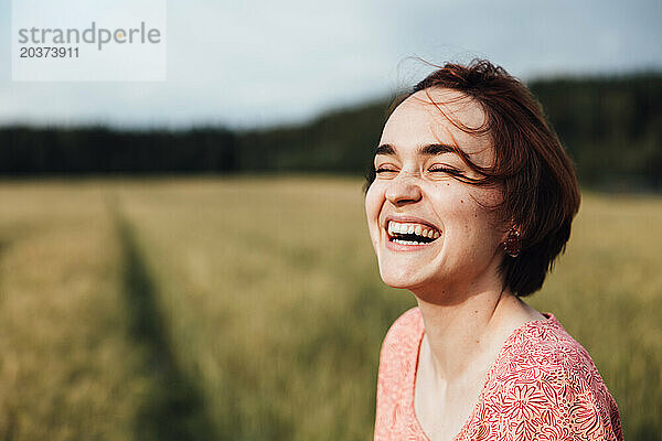 Porträt eines glücklichen Mädchens  das auf einem Feld lacht