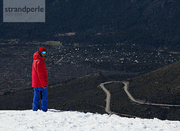 Ein Snowboarder  Der Eine Leuchtend Rote Jacke Auf Einem Verschneiten Bergrücken Am Cerro Catedral  Argentinien  Trägt