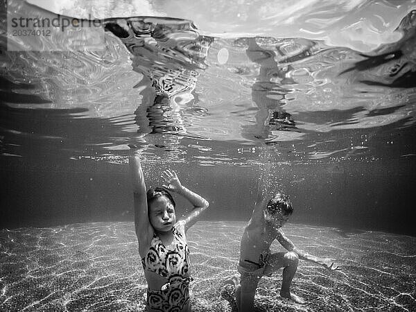 Kinder posieren im Sommer unter Wasser im Pool