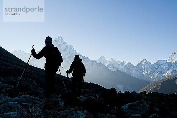 Silhouetten von Wanderern vor der Bergkulisse bei Sonnenaufgang über Dhugla  16.000 Fuß – Wanderung zum Berg. Everst-Basislager.