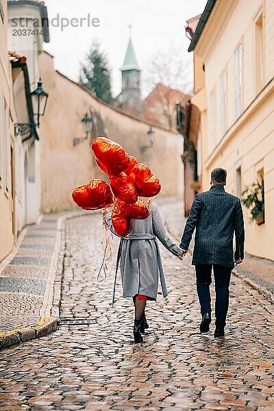 Junges Paar geht mit Luftballons im Herzen durch Prag