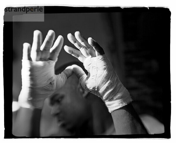 An African American boxer holds his white gloved hands in front of his face. (Polaroid)