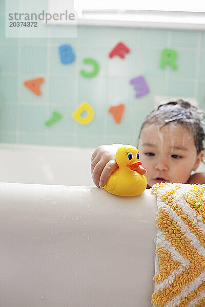 Ein junges asiatisch-amerikanisches Mädchen mit einem Gummientchen in der Badewanne  30. Januar 2011.