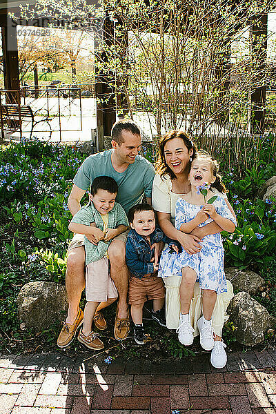 Familie mit kleinen Kindern lacht gemeinsam in der Gartensonne