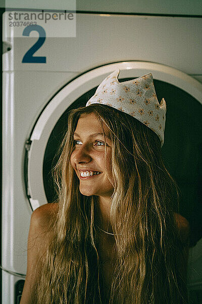 Eine junge Frau wäscht in einer öffentlichen Wäscherei Wäsche und hat Spaß.
