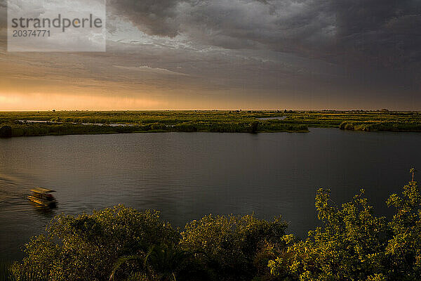 Die Sonne geht am Sambesi unter  während eine Bootssafari zur Mowana Lodge in Botswana zurückkehrt.