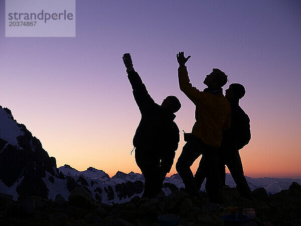 Zwei Kletterer zeichnen sich als Silhouetten gegen den Himmel ab und weisen auf die Route hin.