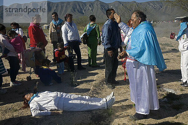 Ein Medium betet vor einem Pilger  der während der Nino-Fidencio-Feierlichkeiten in Espinazo  Bundesstaat Nuevo León  Mexiko  in einem Bett in der Wüste liegt