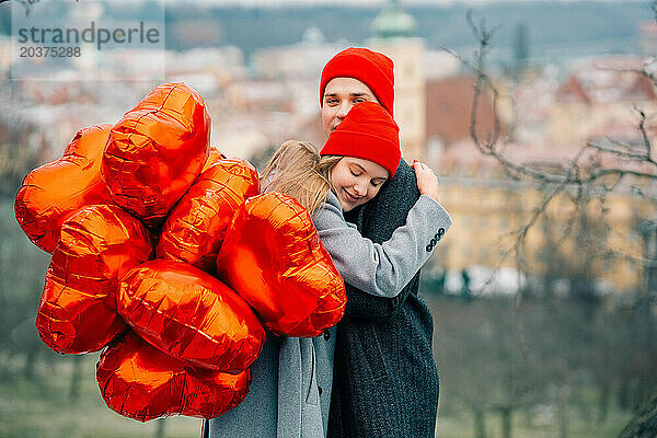 Junges Paar geht mit Luftballons im Herzen durch Prag