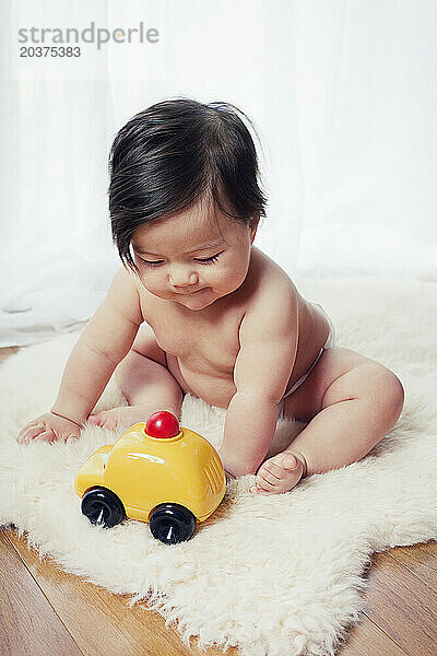 Ein Baby sitzt auf und spielt mit einem Spielzeugauto in New York  New York.