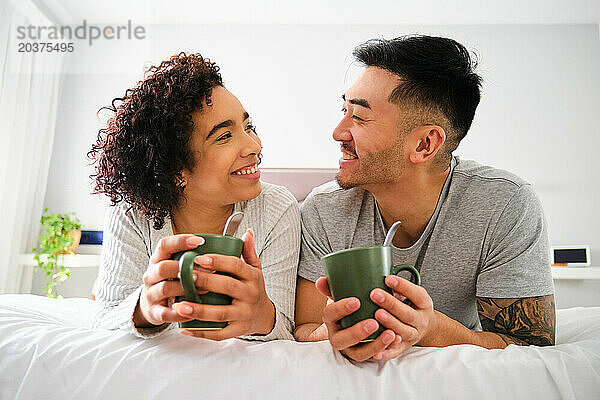Multiethnisches glückliches Paar  das sich im Bett liebevoll anschaut.
