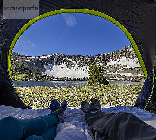 Wanderer ruhen sich in ihrem Zelt aus und blicken auf einen ruhigen See