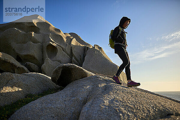 Blick auf eine junge Frau beim Wandern auf Felsen an der Küste  Sardinien  Italien