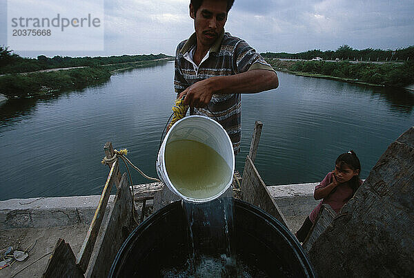 Eine 13-köpfige Familie  die in einem Haus in Reynosa  Mexiko  lebt und zum Waschen Wasser aus einem Kanal in der Nähe ihres Hauses bezieht. Jeden Tag müssen sie ein 200-Liter-Fass damit auffüllen