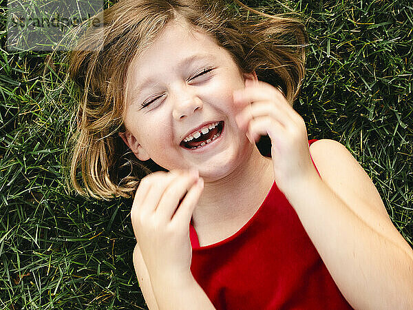 Brünettes Mädchen lacht auf grünem Gras