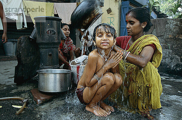 In Wohngebieten in Süd-/Zentral-Kalkutta  Indien  besuchen Frauen Röhrenbrunnen zum Baden  Waschen von Kleidung und zum Auffüllen von Wasser für Trink-/Haushaltszwecke.